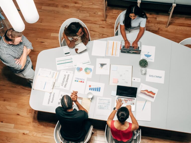 Overhead view of a marketing team collaborating around a table with charts and laptops