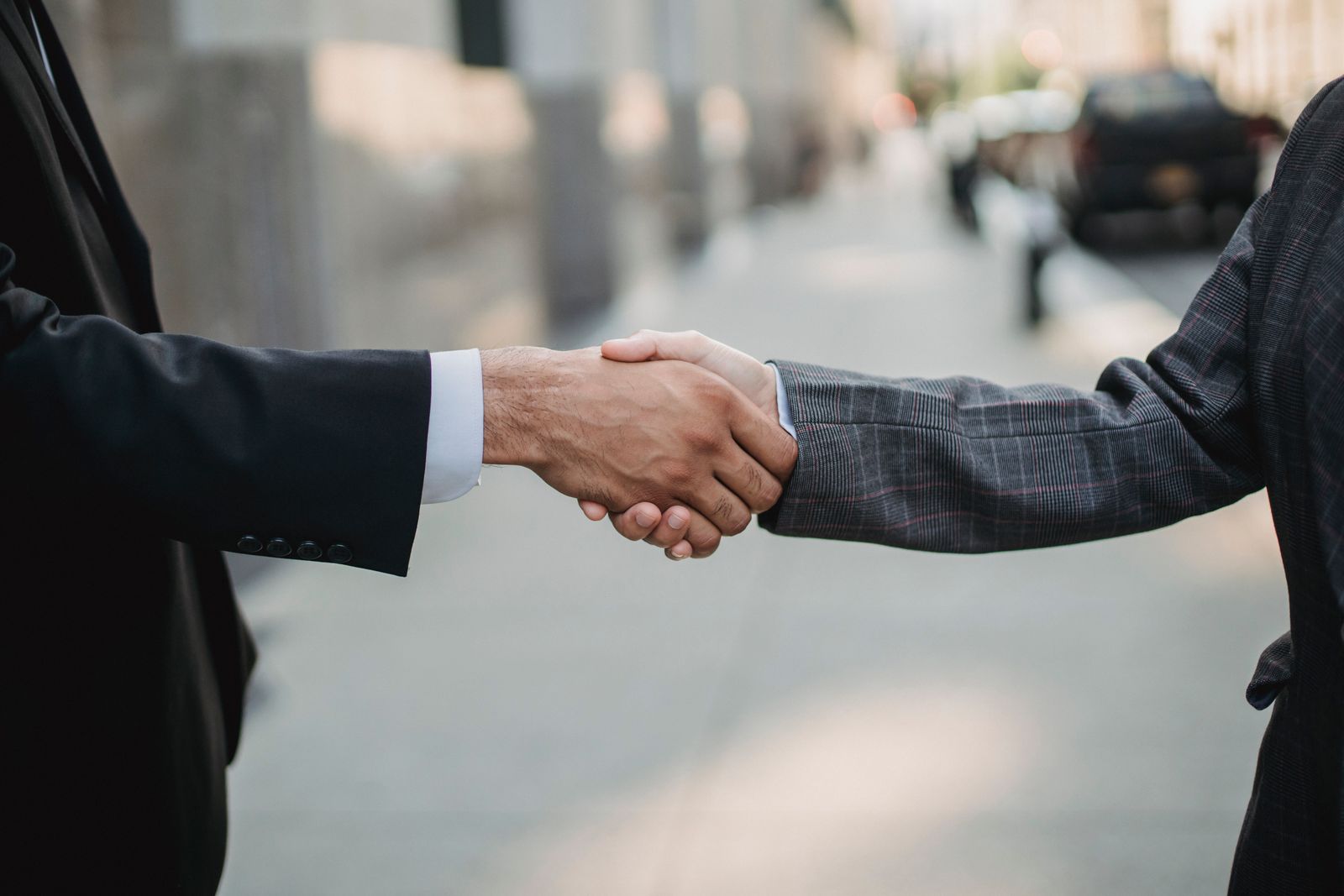 Two business professionals shaking hands outdoors, symbolizing a new connection